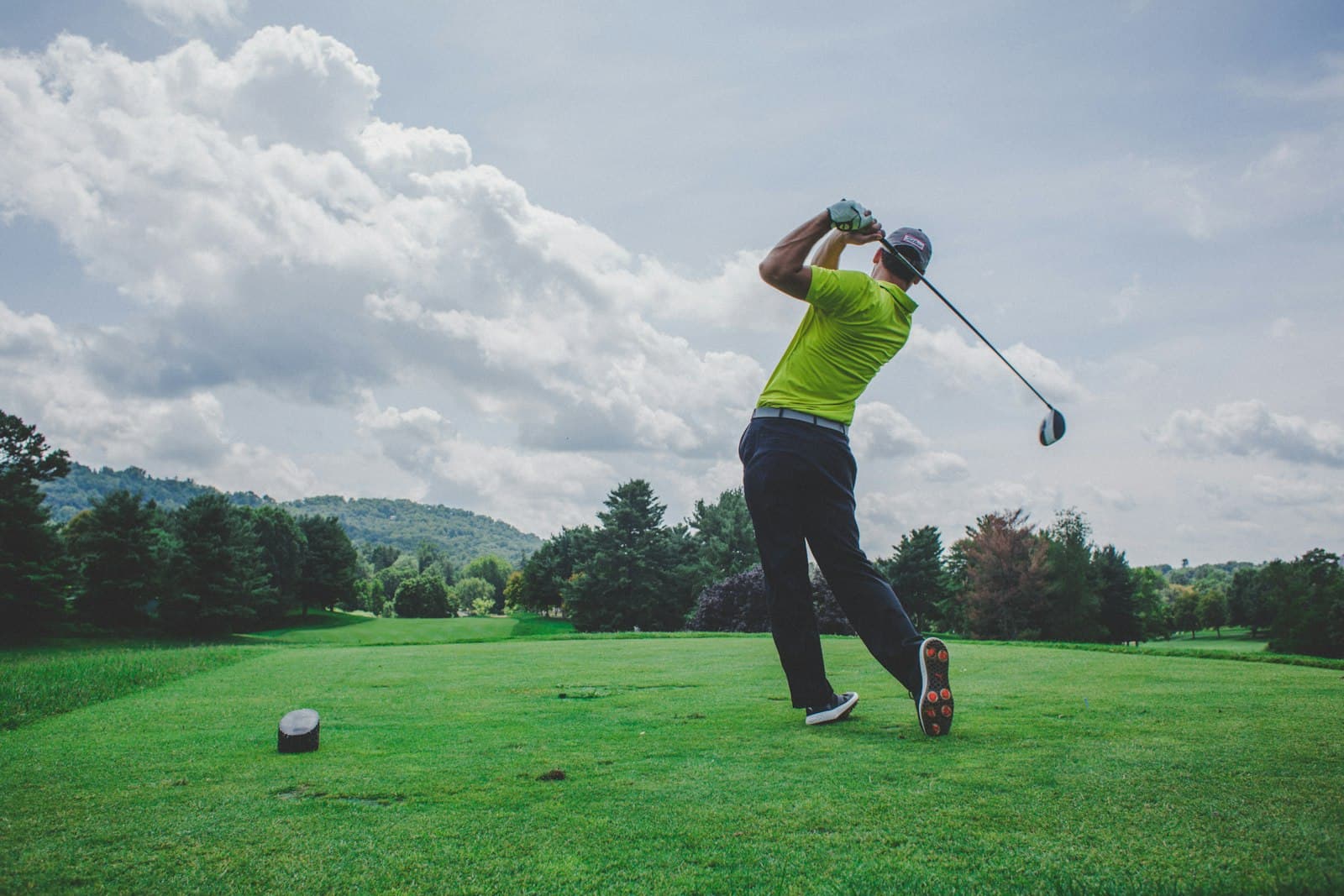 A golfer mid-swing on a sunlit fairway